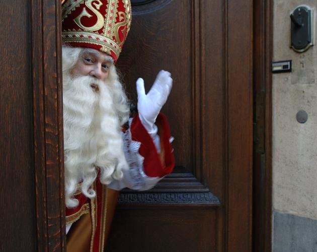 Sinterklaas zwaait aan de deur van zijn huis